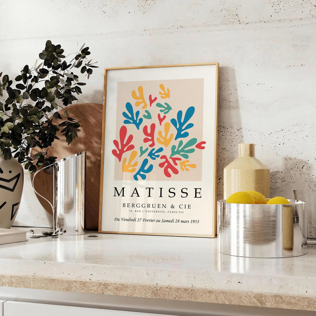 Poster showing colorful abstract paper cutouts in Matisse style artwork - styled on a counter with eucalyptus and a bowl of lemons