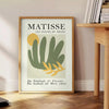 Gray and white poster featuring Matisse-inspired paper cutout abstract composition - beside a round wooden side table with books