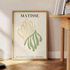 Poster showing Matisse paper cutouts artwork with gray and yellow - beside a round wooden side table with books