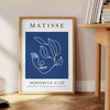 Black and white Matisse cut-outs poster, abstract papier découpés artwork - beside a round wooden side table with books