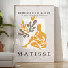 Poster showing Matisse-style papier découpés with bold colorful abstract shapes - in a bright minimalist room with a plant and an armchair