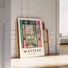 Matisse-inspired cutout design with orange and blue shapes - leaning on a herringbone floor against a white panelled wall