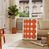 Abstract composition with orange and earthy brown tones in a modern style - in a Parisian living room with a sofa and a fig plant