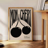 Abstract design featuring cherries in black and orange hues - beside a round wooden side table with books
