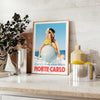 Vintage Reiseposter von Monte Carlo mit gelben und blauen Farbtönen - auf einer Arbeitsplatte mit Eukalyptus und einer Schale Zitronen