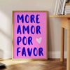 Abstract design featuring the phrase 'Más Amor Por Favor' in blue and purple tones - beside a round wooden side table with books