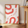 Red and white motivational poster with abstract space elements and inspirational text - beside a round wooden side table with books