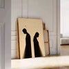 Minimalistische menschliche Figur in Schwarz- und Orangetönen - an eine weiße Paneelwand gelehnt auf Fischgrätparkett