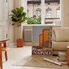 Illustration of Napoli with green and orange colors, featuring iconic landmarks - in a Parisian living room with a sofa and a fig plant