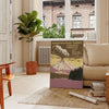 Illustration of a national park with mountains and trees in muted colors - in a Parisian living room with a sofa and a fig plant