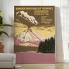 Illustration of a national park with mountains and trees in muted colors - in a bright minimalist room with a plant and an armchair
