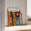 Abstract nature scene with polka dots in orange and green by Yayoi Kusama - leaning on a herringbone floor against a white panelled wall