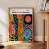 Abstract nature scene with polka dots in orange and green by Yayoi Kusama - beside a round wooden side table with books