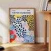 Colorful abstract nature scene by Yayoi Kusama with polka dots - beside a round wooden side table with books