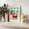 Illustration of a Negroni cocktail with orange and blue accents - styled on a counter with eucalyptus and a bowl of lemons