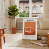 Illustration of a Negroni cocktail in orange and black tones - in a Parisian living room with a sofa and a fig plant