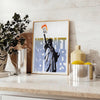 A travel poster featuring New York's skyline in black and orange hues - styled on a counter with eucalyptus and a bowl of lemons