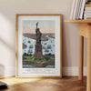 A travel poster featuring New York City with green and blue hues - beside a round wooden side table with books