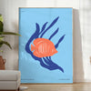 A colorful depiction of ocean wildlife featuring orange and blue hues - in a bright minimalist room with a plant and an armchair