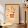 An illustration of an Old Fashioned cocktail with orange and red hues - beside a round wooden side table with books
