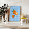 A bold orange kitchen poster featuring cooking utensils and ingredients in a modern style - styled on a counter with eucalyptus and a bowl of lemons