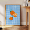 A bold orange kitchen poster featuring cooking utensils and ingredients in a modern style - beside a round wooden side table with books