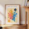 Layered paper cut design featuring abstract shapes in orange and blue - beside a round wooden side table with books