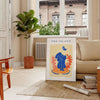 Papier découpé artwork featuring intricate cut-out designs in orange and blue - in a Parisian living room with a sofa and a fig plant