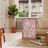 Minimalist paper-cut artwork in white and brown, layered abstract design - in a Parisian living room with a sofa and a fig plant