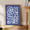 Gray and white space-themed poster featuring layered paper-cut artwork - beside a round wooden side table with books