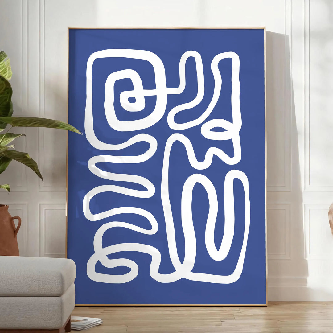 Gray and white space-themed poster featuring layered paper-cut artwork - in a bright minimalist room with a plant and an armchair
