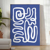 Gray and white space-themed poster featuring layered paper-cut artwork - in a bright minimalist room with a plant and an armchair
