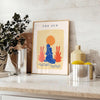 Poster showing layered papier découpé space artwork in orange and blue - styled on a counter with eucalyptus and a bowl of lemons