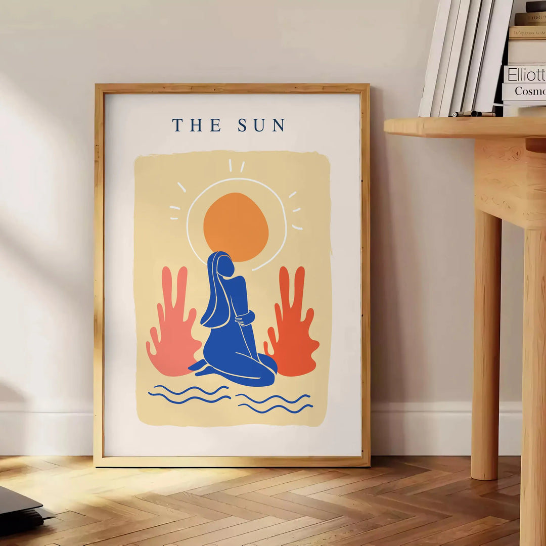 Poster showing layered papier découpé space artwork in orange and blue - beside a round wooden side table with books