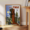 Retro travel poster featuring the Eiffel Tower and a TWA airplane - beside a round wooden side table with books