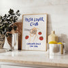 blue and white poster featuring 'Pasta Lover Club' text with pasta illustrations - styled on a counter with eucalyptus and a bowl of lemons