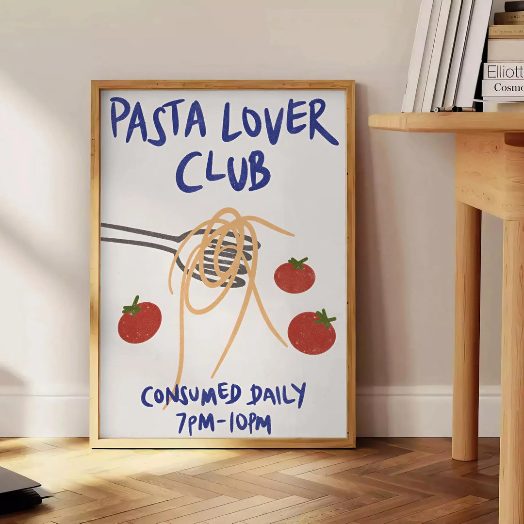 Minimalist kitchen print featuring 'Pasta Lover Club' in white and gray tones - beside a round wooden side table with books