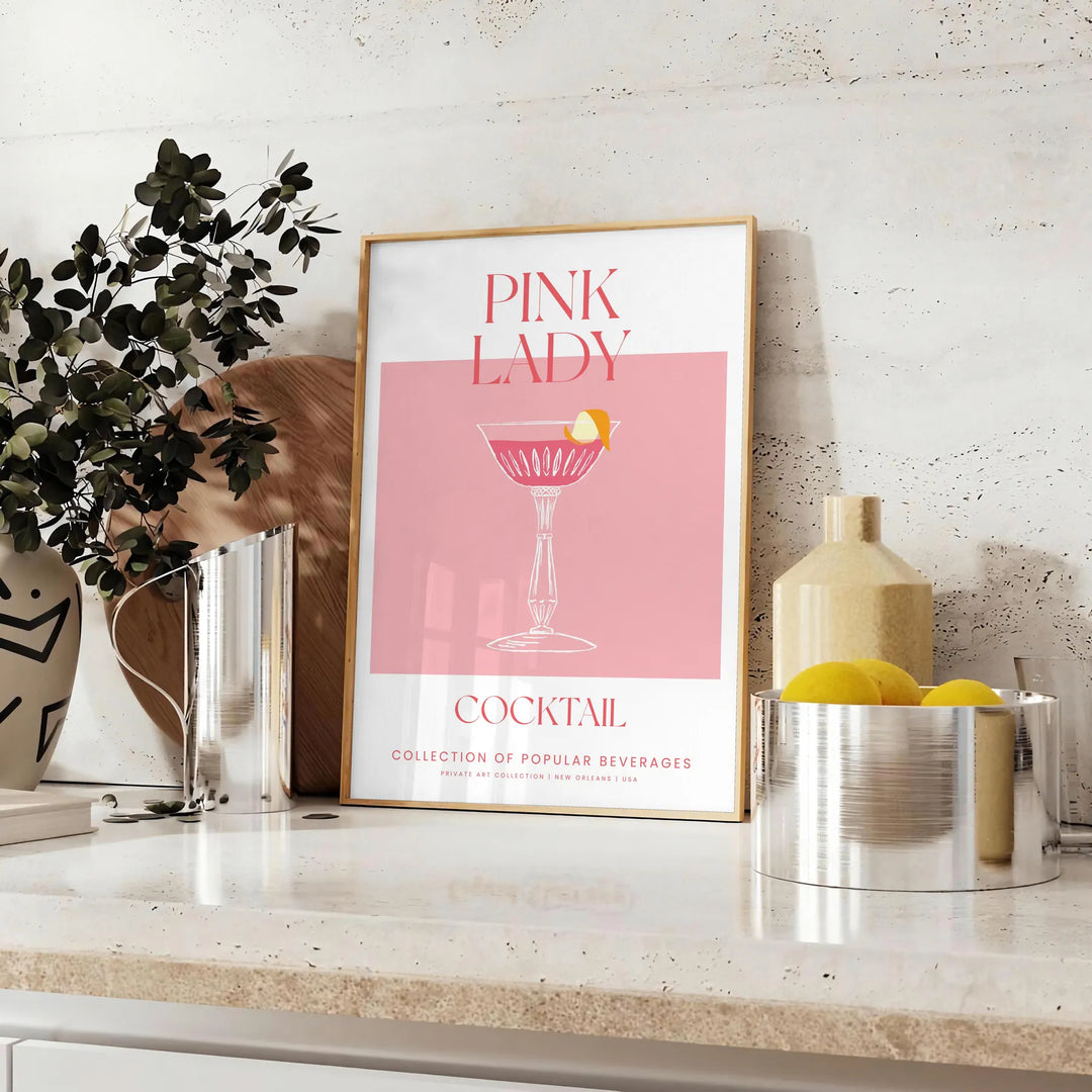 Kolorowa ilustracja koktajlu Pink Lady w odcieniach pomarańczowym i różowym - na blacie z eukaliptusem i miską cytryn