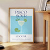 Εικονογράφηση ενός κοκτέιλ Pisco Sour με πράσινες και μπλε αποχρώσεις - δίπλα σε στρογγυλό ξύλινο βοηθητικό τραπέζι με βιβλία