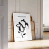 Botanical illustration featuring graceful plant designs in gray and black tones - leaning on a herringbone floor against a white panelled wall