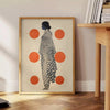 Stylish gray poster with vibrant orange abstract shapes - beside a round wooden side table with books