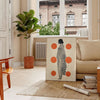 Stylish gray poster with vibrant orange abstract shapes - in a Parisian living room with a sofa and a fig plant