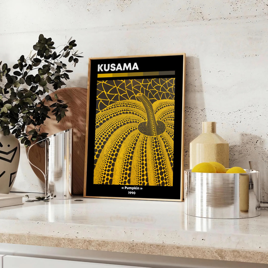 Dynia pokryta kropkami autorstwa Yayoi Kusama, w dominujących czerniach i pomarańczach - na blacie z eukaliptusem i miską cytryn