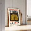 Yellow and orange pumpkin with polka dots by Yayoi Kusama - leaning on a herringbone floor against a white panelled wall