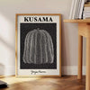 A bright orange pumpkin covered in black polka dots by Yayoi Kusama - beside a round wooden side table with books