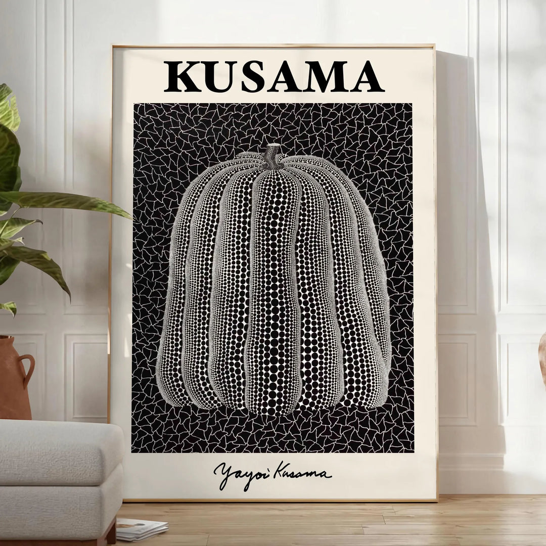 A bright orange pumpkin covered in black polka dots by Yayoi Kusama - in a bright minimalist room with a plant and an armchair