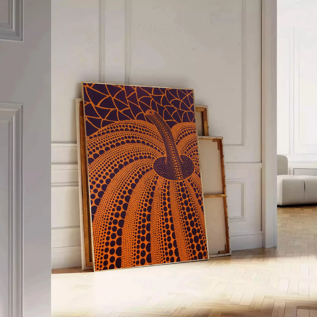 Yayoi Kusama pumpkin artwork with rich brown and green hues - leaning on a herringbone floor against a white panelled wall