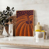 Yayoi Kusama pumpkin artwork with rich brown and green hues - styled on a counter with eucalyptus and a bowl of lemons