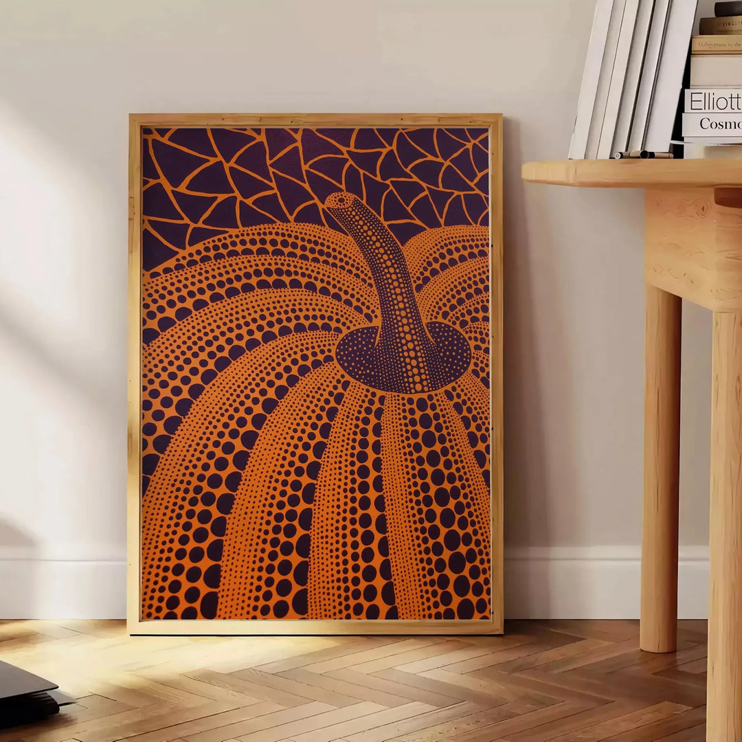 Yayoi Kusama pumpkin artwork with rich brown and green hues - beside a round wooden side table with books
