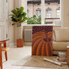 Yayoi Kusama pumpkin artwork with rich brown and green hues - in a Parisian living room with a sofa and a fig plant